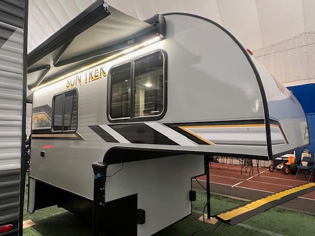 A white trailer with a canopy is parked in a parking lot.