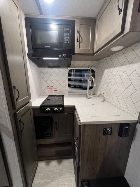 A kitchen with a stove, microwave, sink and cabinets.