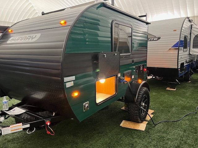 A green and black trailer is sitting on top of a lush green field.