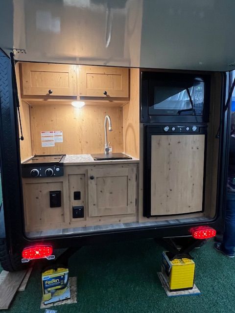 The back of a trailer with a kitchen and a sink.