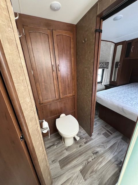 A bathroom with a toilet and a bed in the background