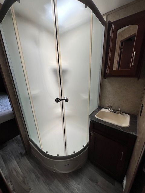 A bathroom with a shower, sink, and mirror.