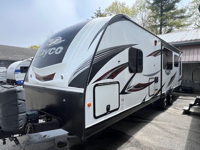 A white and black trailer is parked in front of a building.