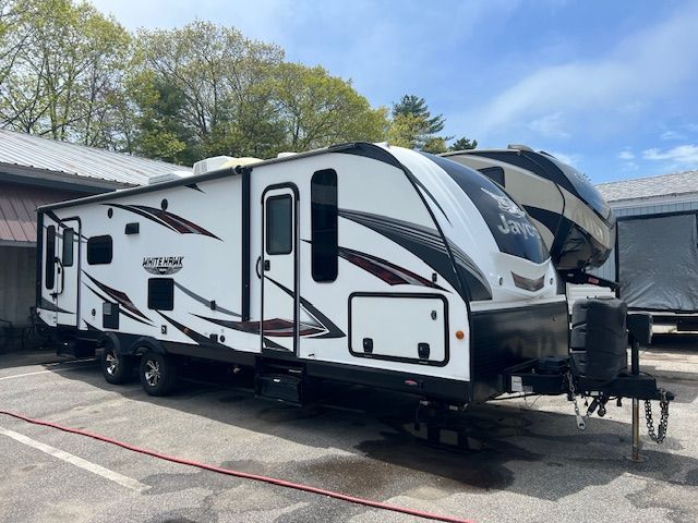A white and black trailer is parked in a parking lot.