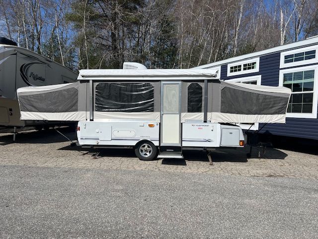 A white Pop Up Camper is parked in a parking lot.