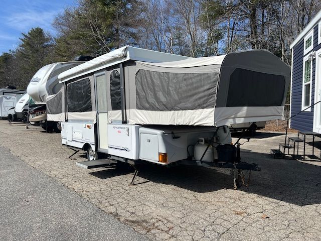 A Pop Up Camper is parked on the side of the road.