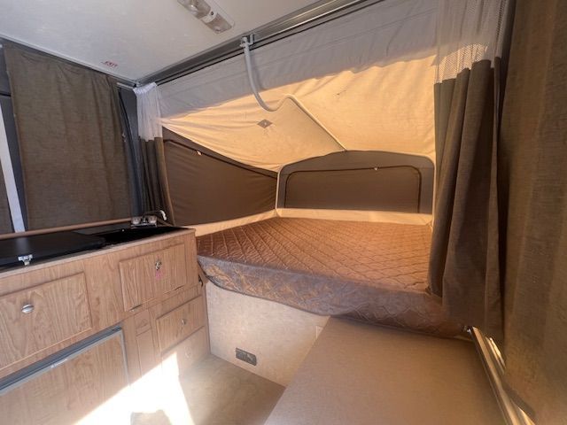A camper with a bed and a sink in it