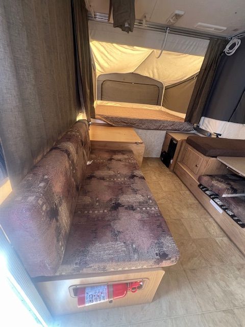 The inside of a camper with a couch and a bed.