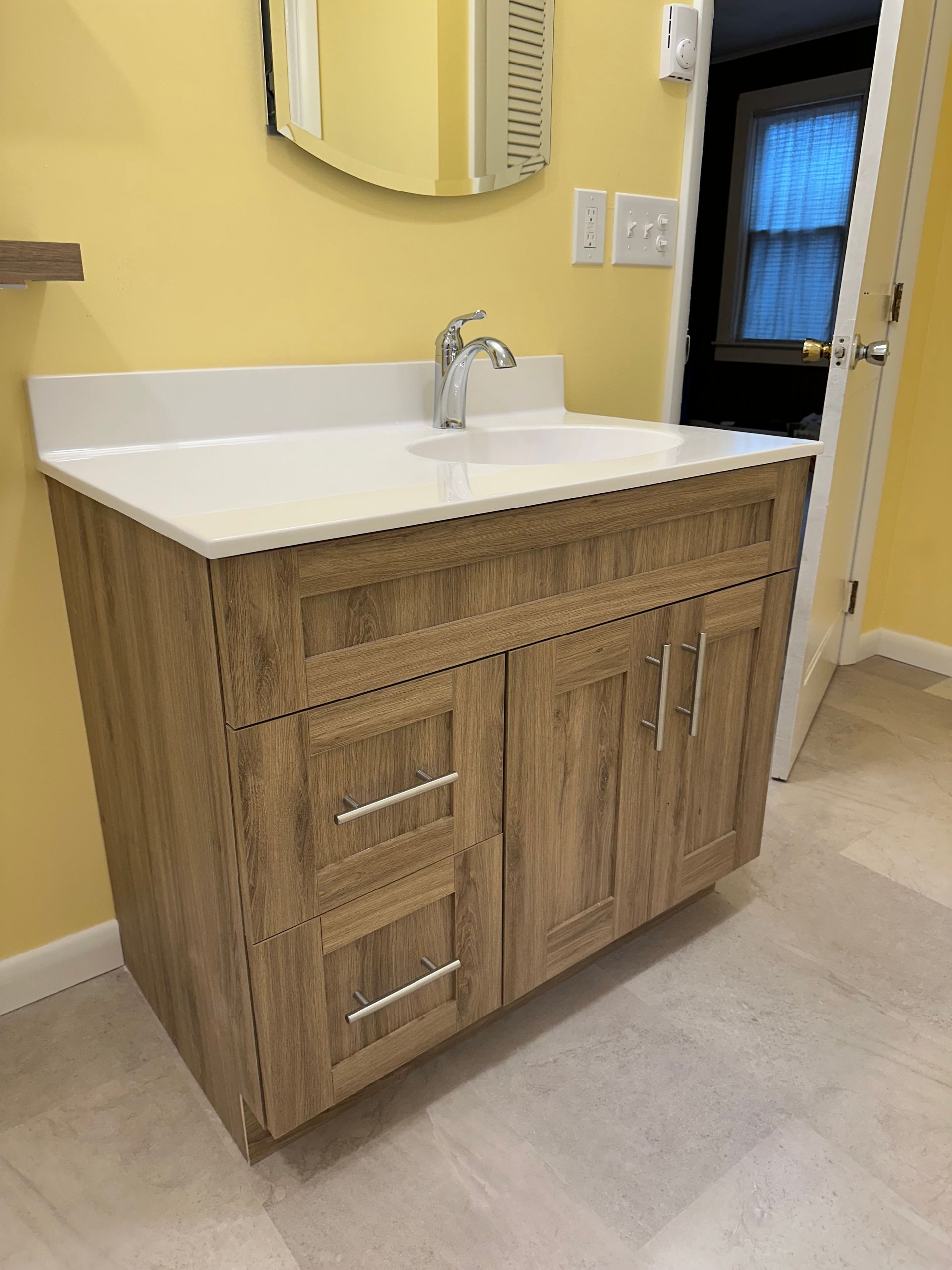 Bathroom vanity with light brown cabinets, white countertop, and silver faucet.