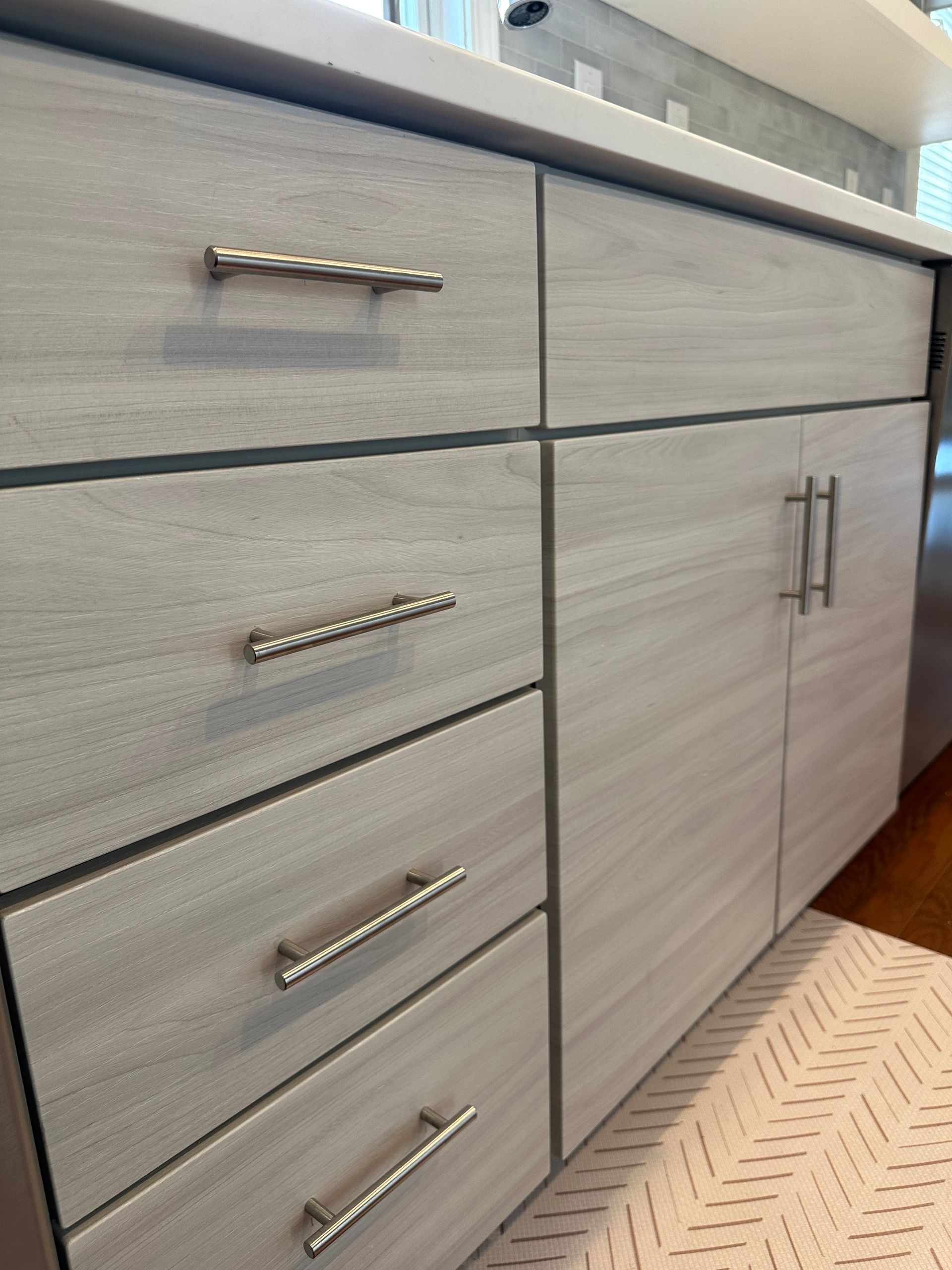 Light gray kitchen cabinets with silver hardware and a white countertop.