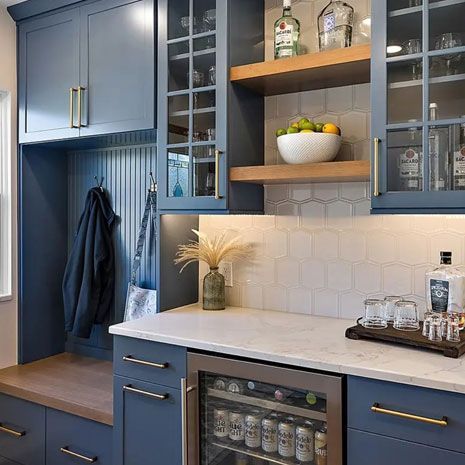 Blue home bar with liquor, glassware, and built-in refrigerator
