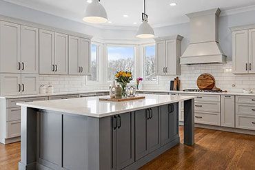 Gray and white kitchen with island, cabinets, white countertops, and hardwood floors