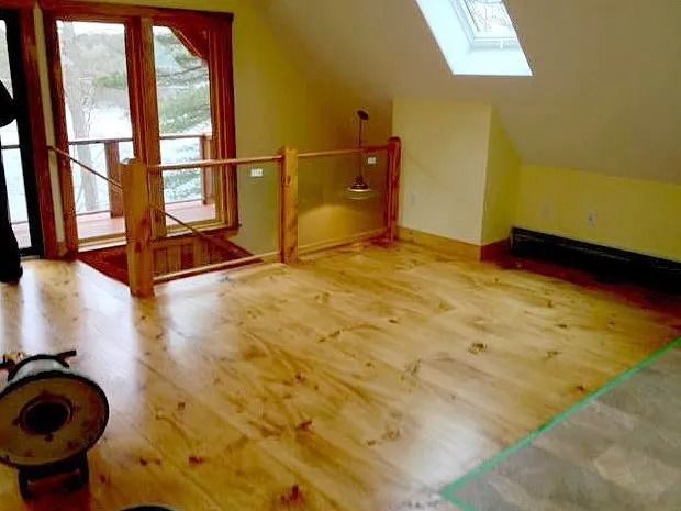 Wooden floored attic space with skylight and railing.