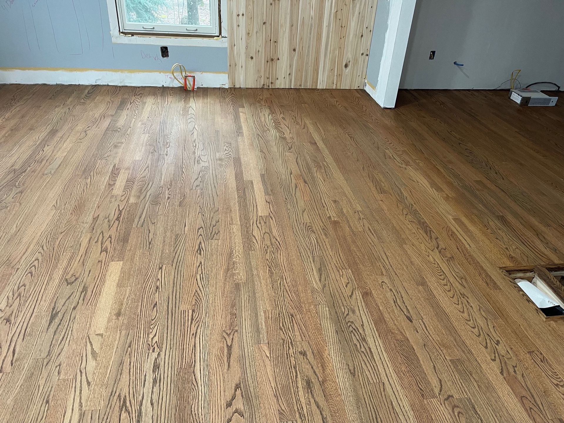 Hardwood floor with a warm brown stain, room under construction.