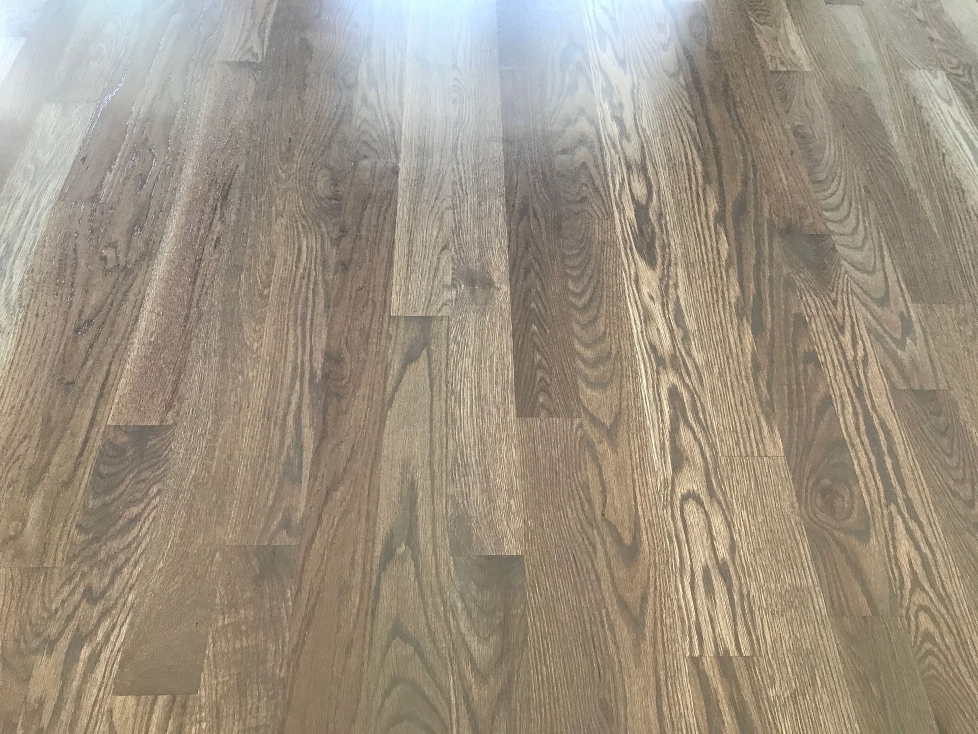 Close-up of hardwood flooring with a weathered gray-brown finish, showing wood grain.