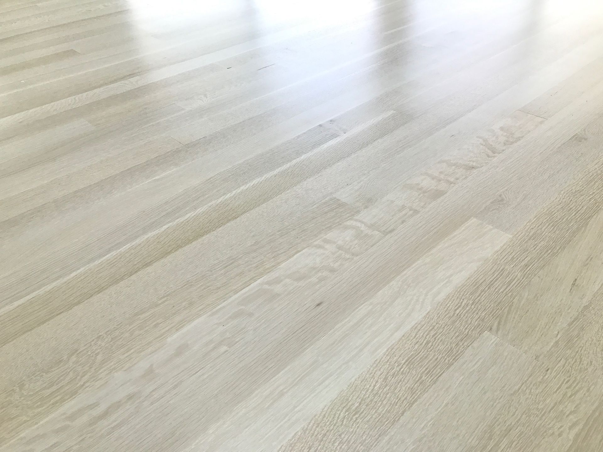Light wood floor with a glossy finish, angled perspective.