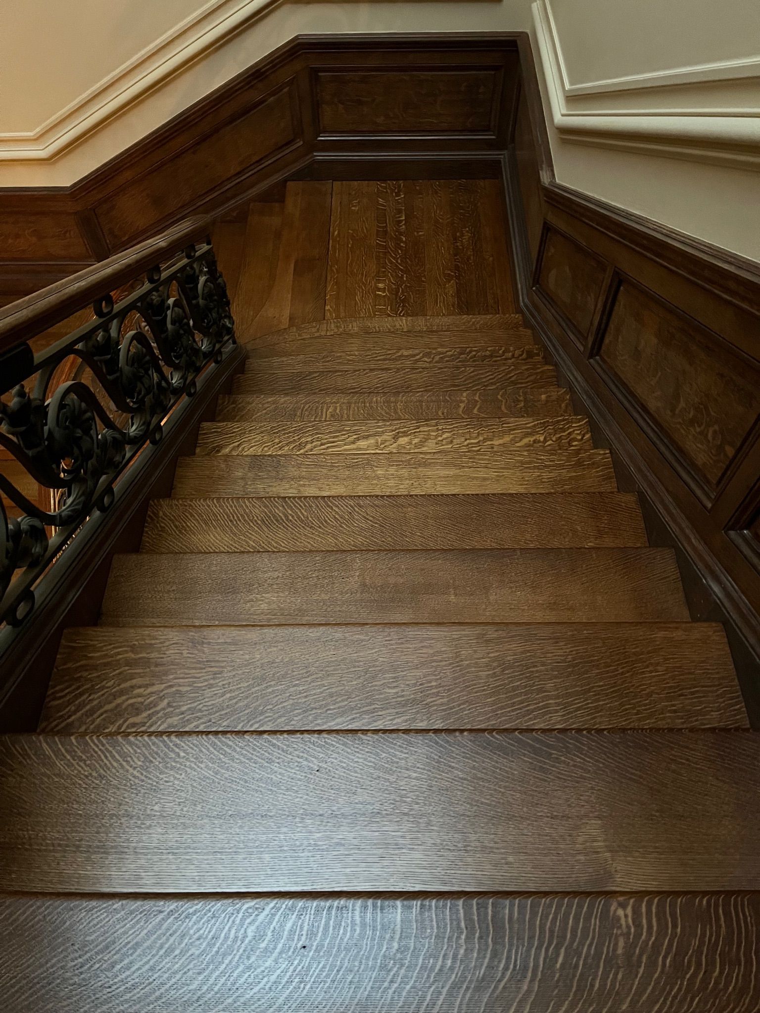 Dark wooden staircase with ornate railing and detailed trim.