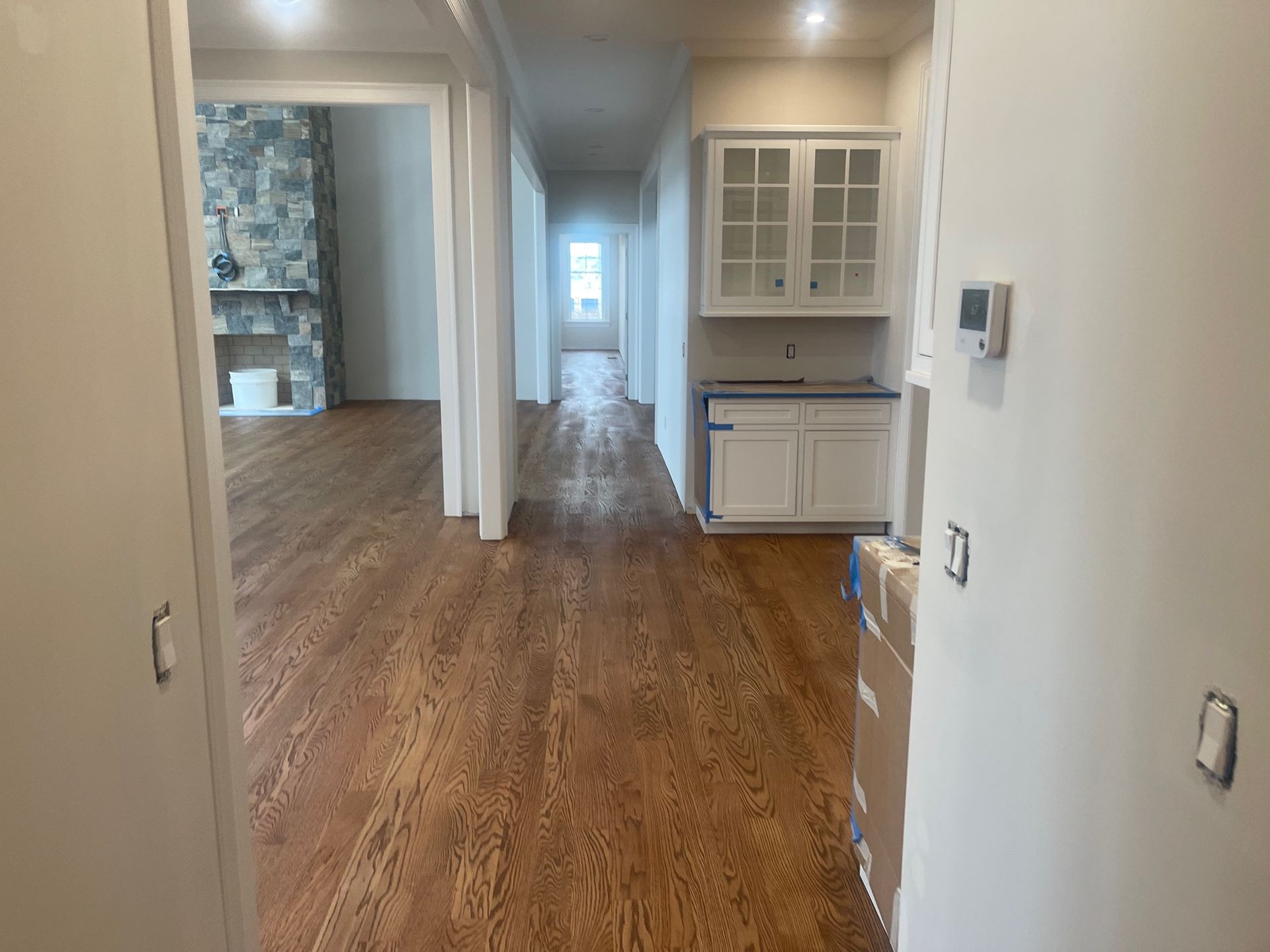 Hallway with wooden floors, built-in cabinets, and a stone fireplace.