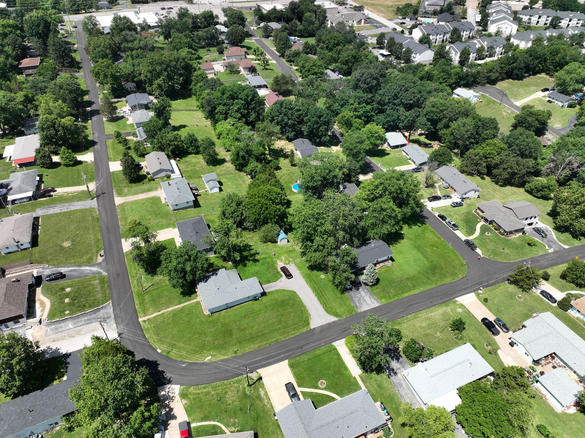 Aerial view of a suburban neighborhood with houses, tree-lined streets, and green lawns