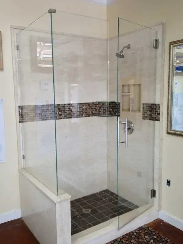 Glass walk-in shower with tiled floor and mosaic accent band in a bathroom