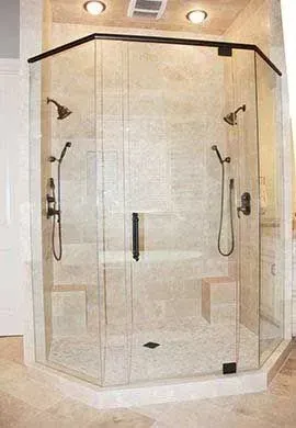 Corner glass shower enclosure with black trim and dual showerheads in a beige tiled bathroom