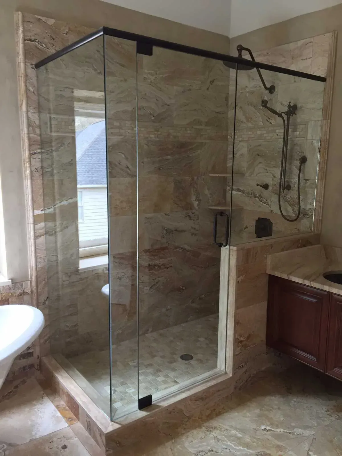 Glass walk-in shower with beige tile, rain showerhead, and a bathroom vanity beside it