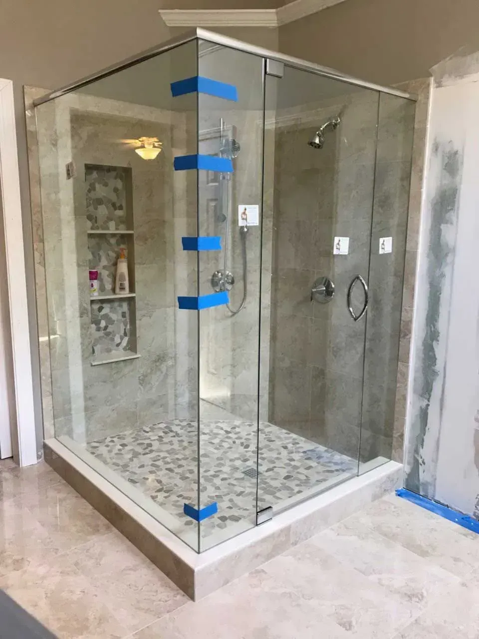 Glass shower enclosure with tiled floor and wall niche in a bathroom