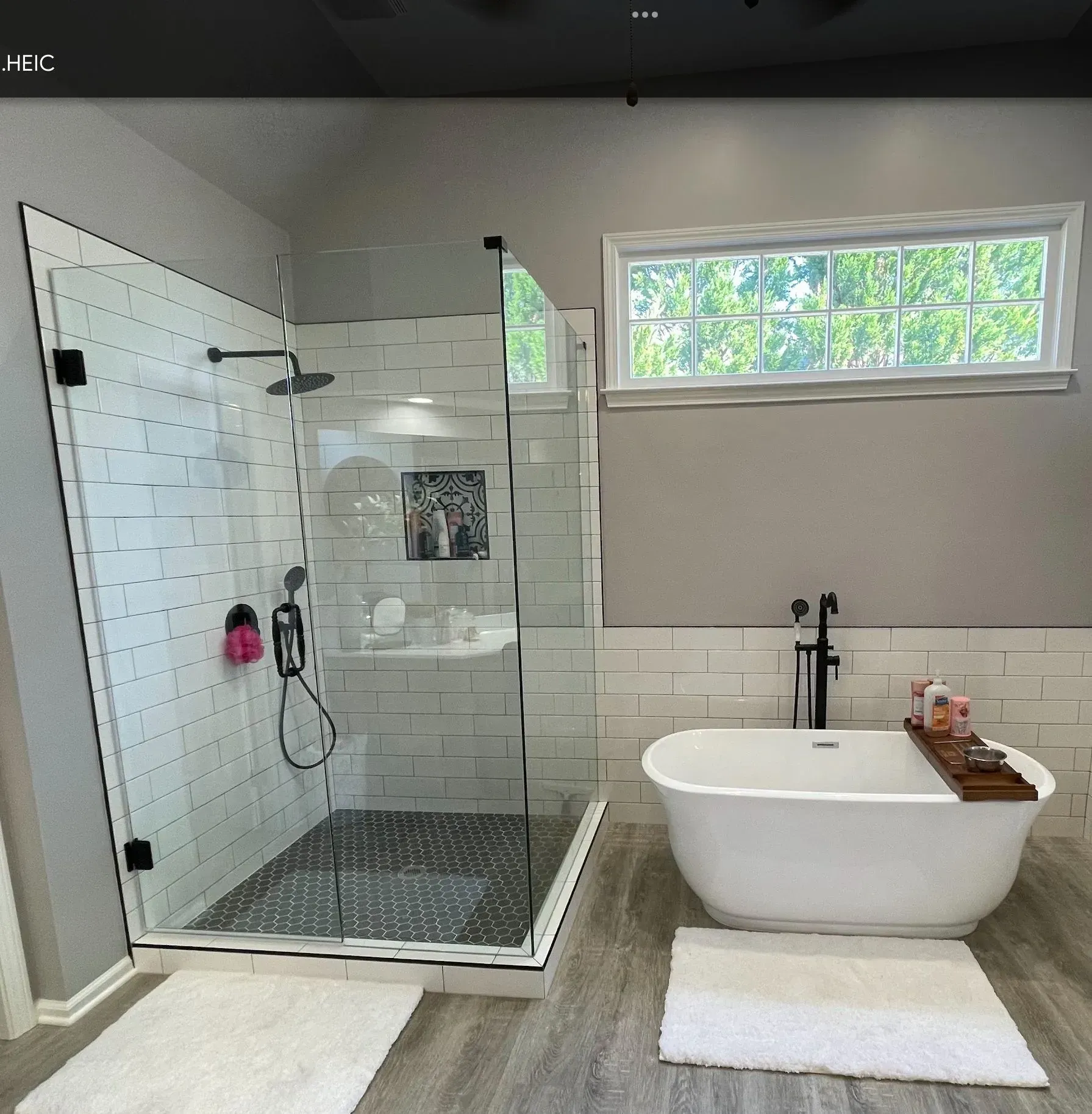 Modern bathroom with glass shower, freestanding tub, and white subway tile accents