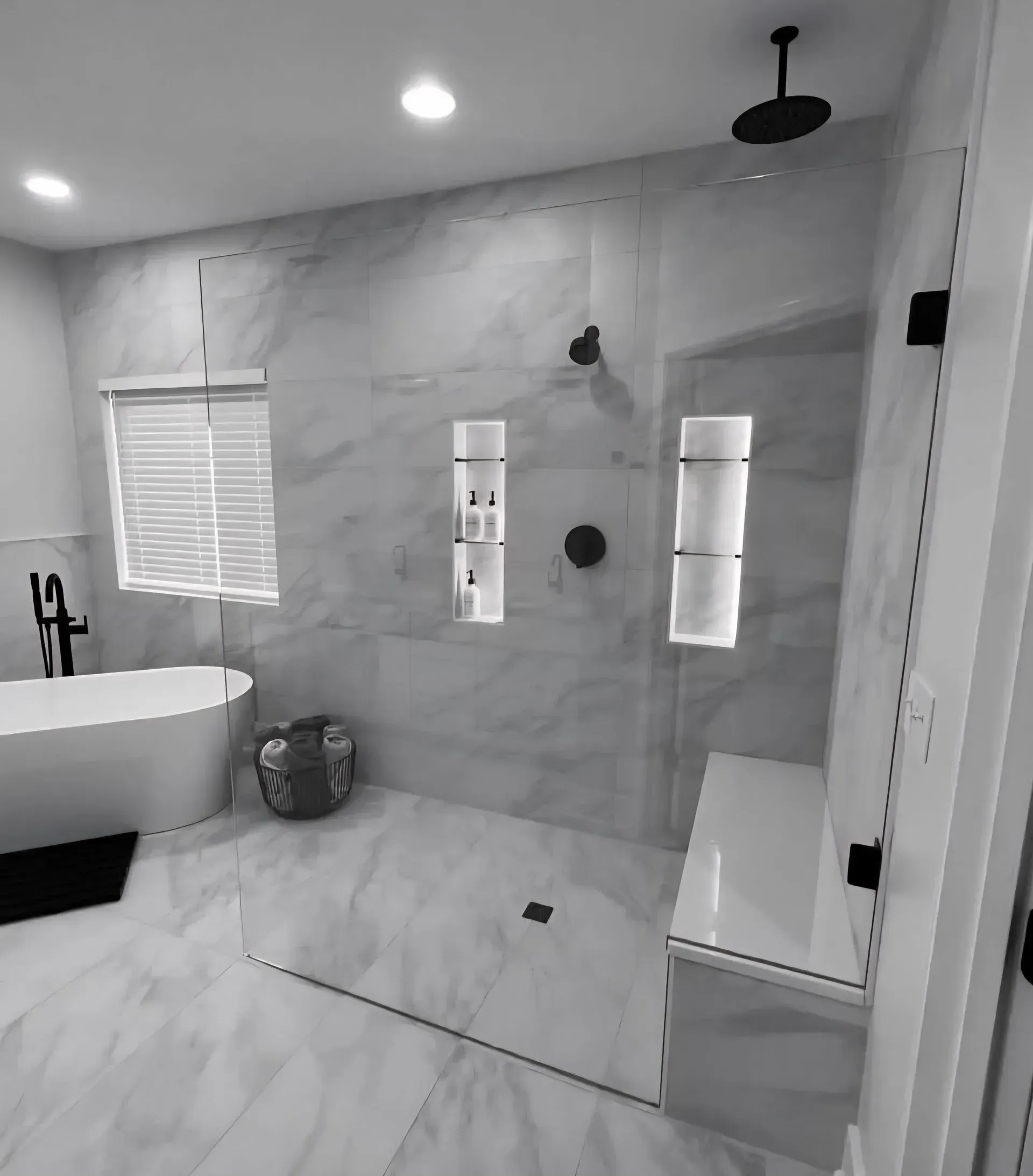 Modern marble bathroom with a freestanding tub, walk-in shower, and bench by a glass door.