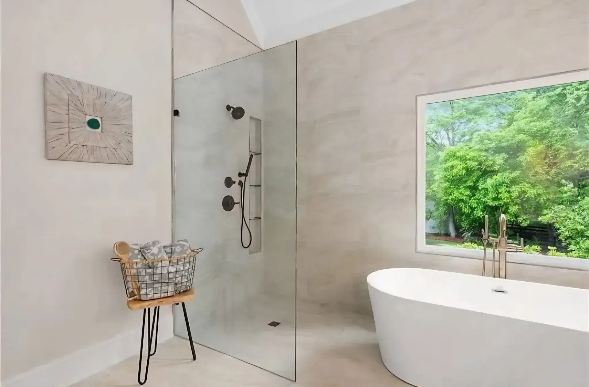 Modern beige bathroom with walk-in shower, freestanding tub, and window view of greenery