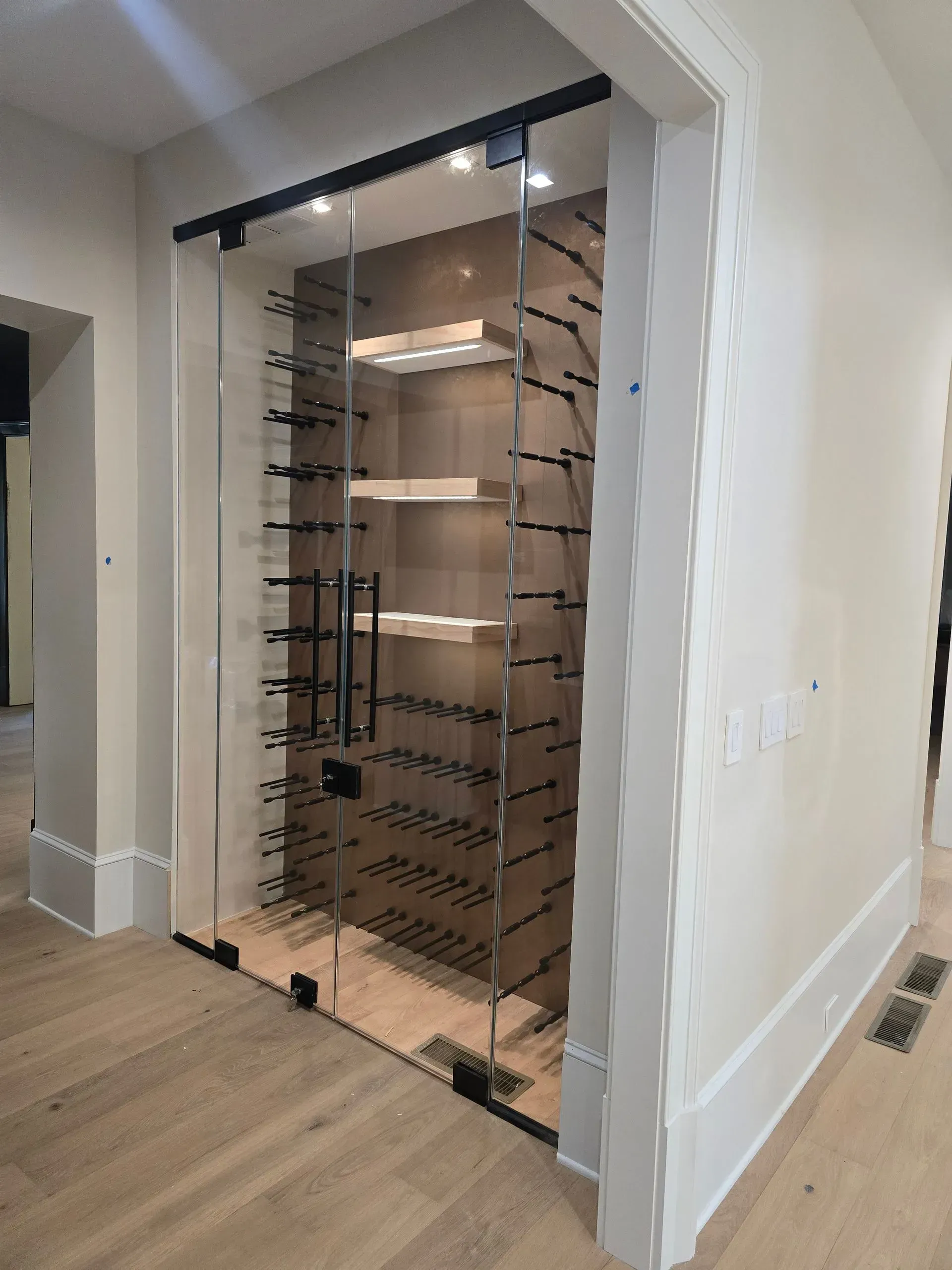 Built-in closet with glass doors and illuminated shelves in a modern hallway opening