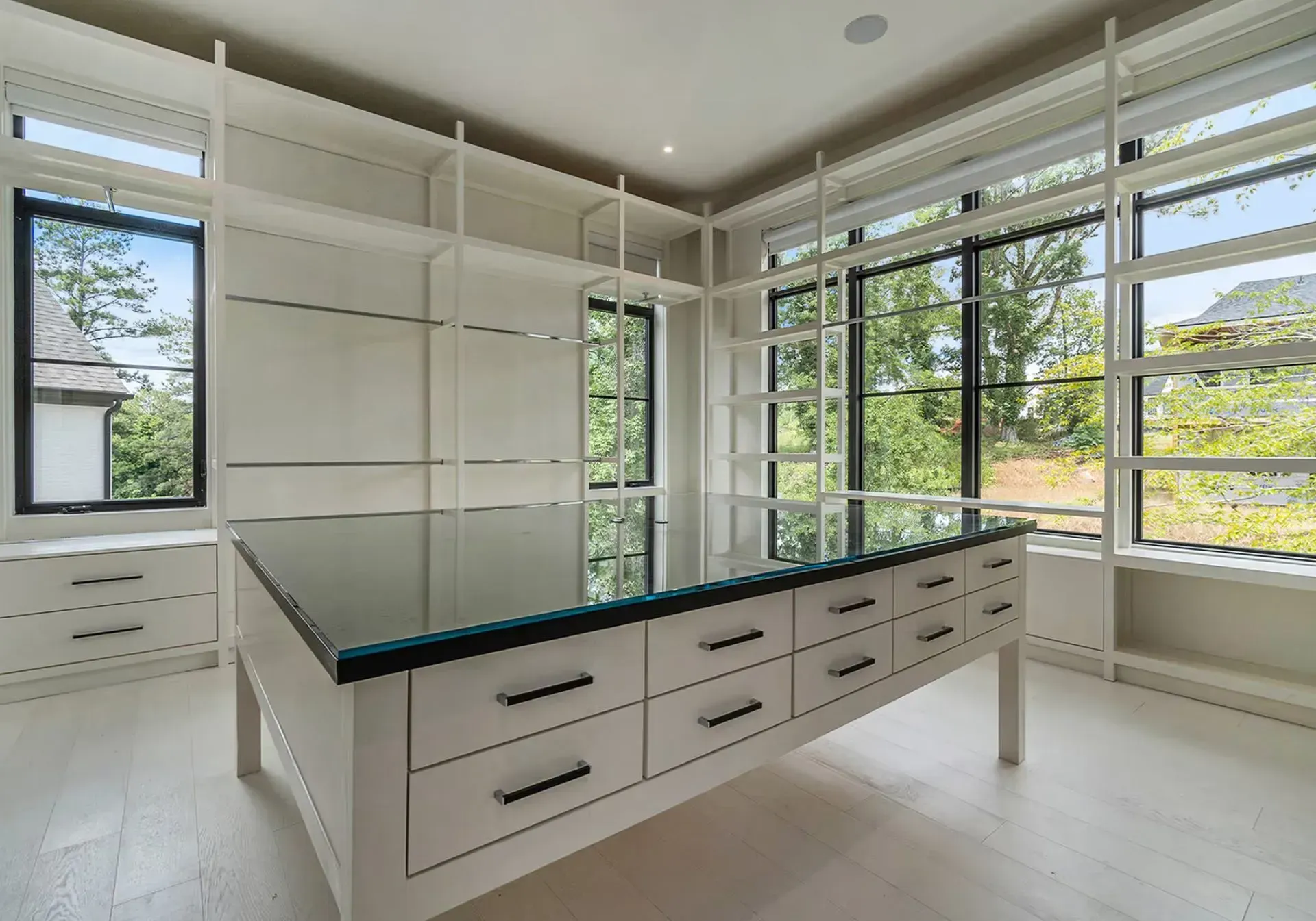 Bright modern kitchen with white cabinets, black island countertop, and large windows overlooking greenery