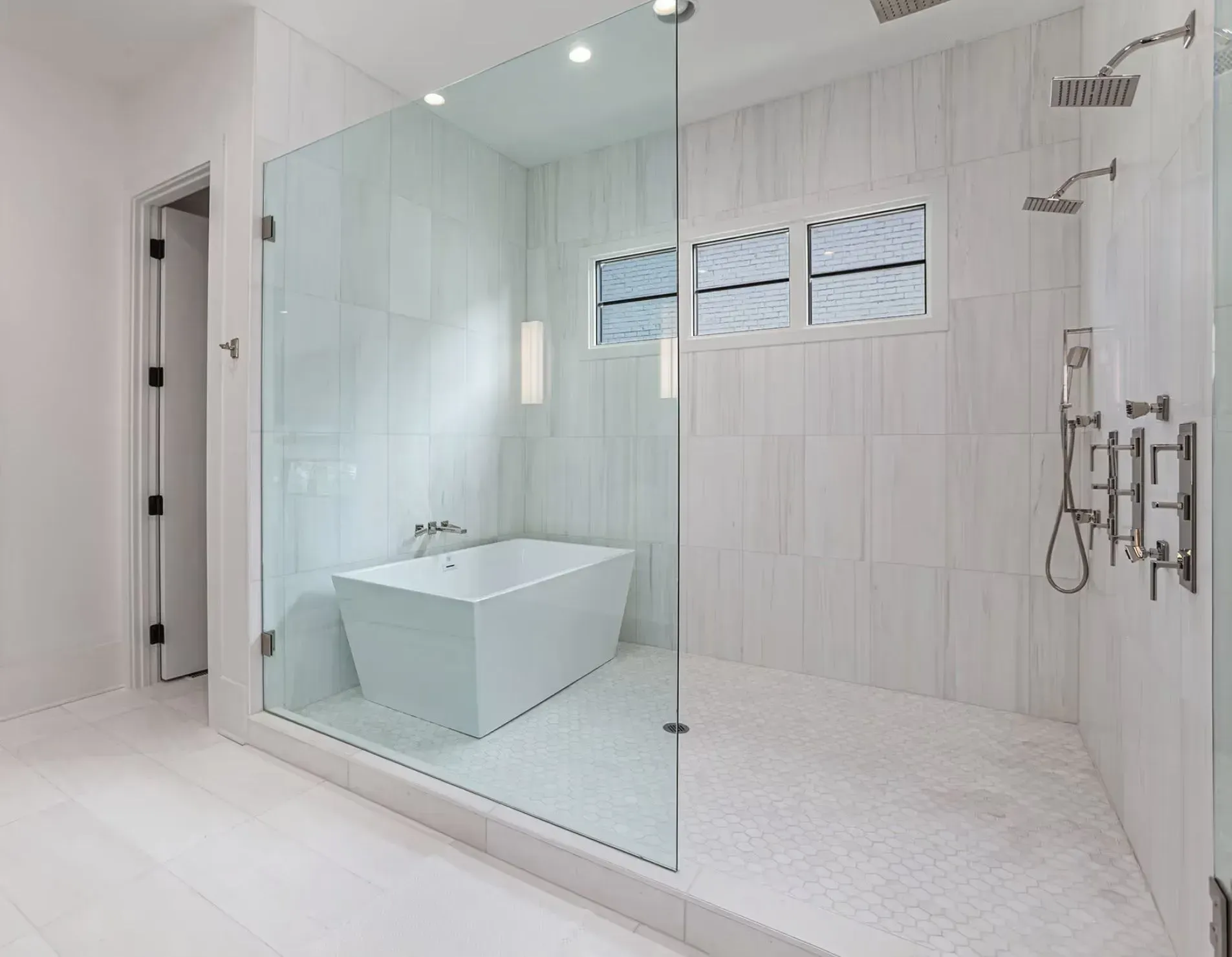 Modern white bathroom with glass shower, freestanding tub, and tiled walls