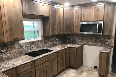 A kitchen with wooden cabinets , granite counter tops , a sink , and a microwave.