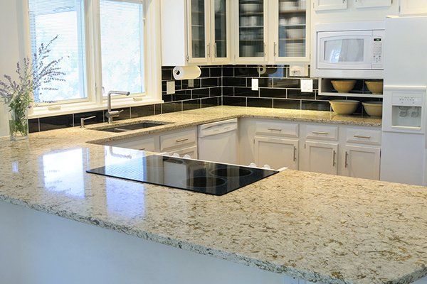A kitchen with granite counter tops and white cabinets.