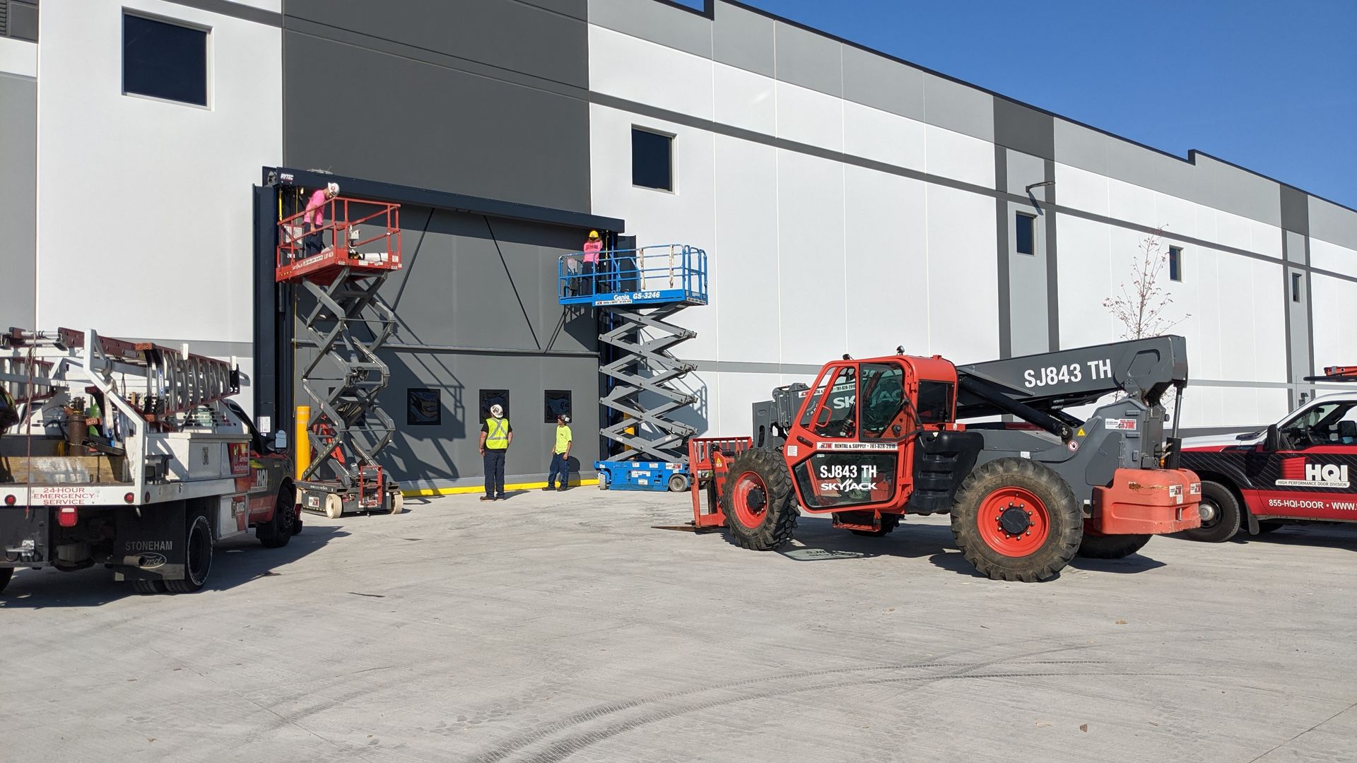 A group of construction vehicles are parked in front of a large building.