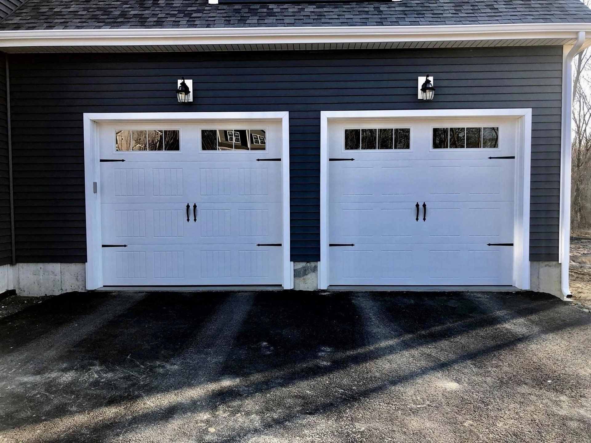 There are two garage doors on the side of a house.