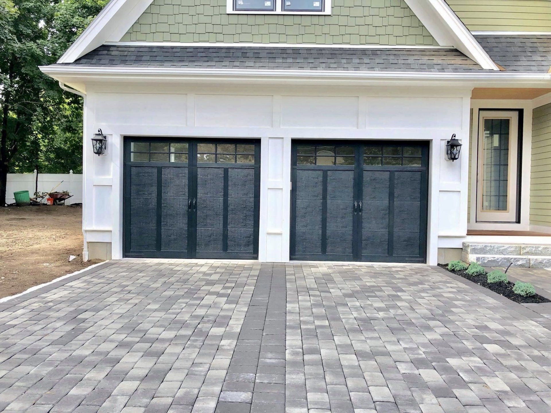 A house with two garage doors and a brick driveway.