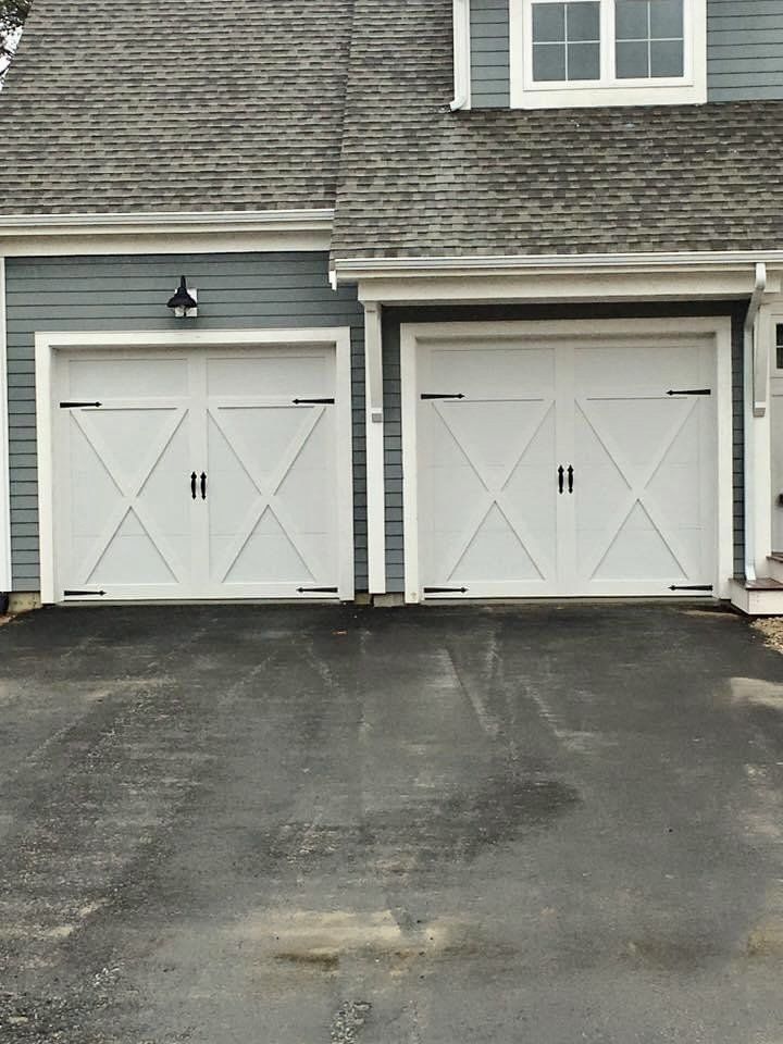 Two white garage doors are sitting next to each other in front of a house.