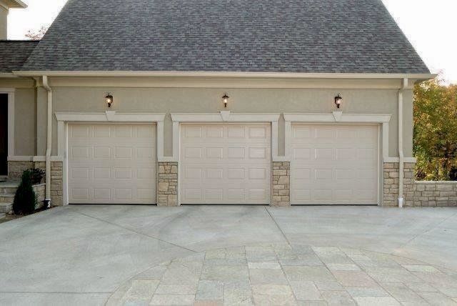 There are three garage doors on the side of a house.