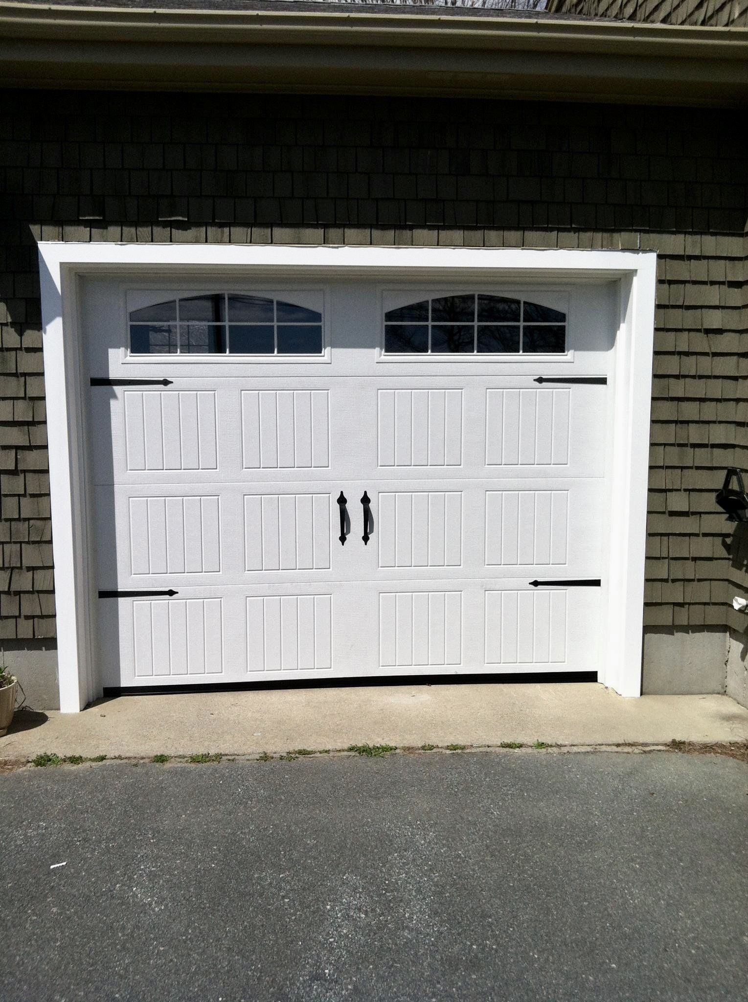 A white garage door is sitting on the side of a brick building.