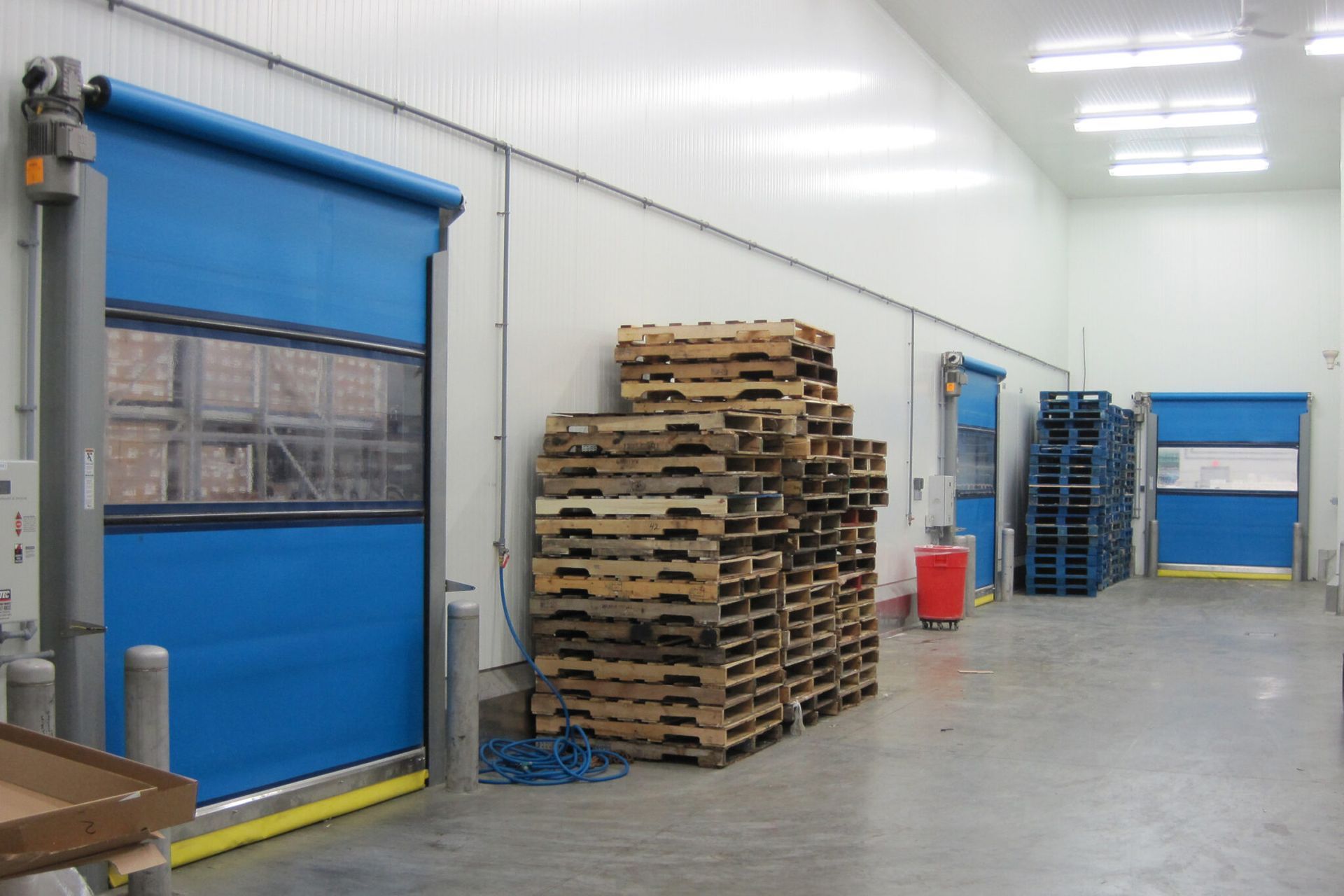 A warehouse filled with pallets and blue doors