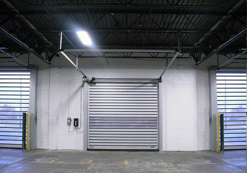 A warehouse with a garage door open and a light on the ceiling.