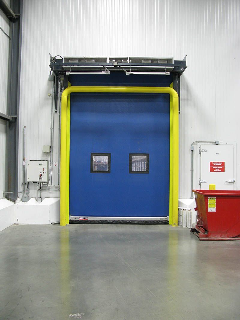 A blue door with a yellow railing in a warehouse