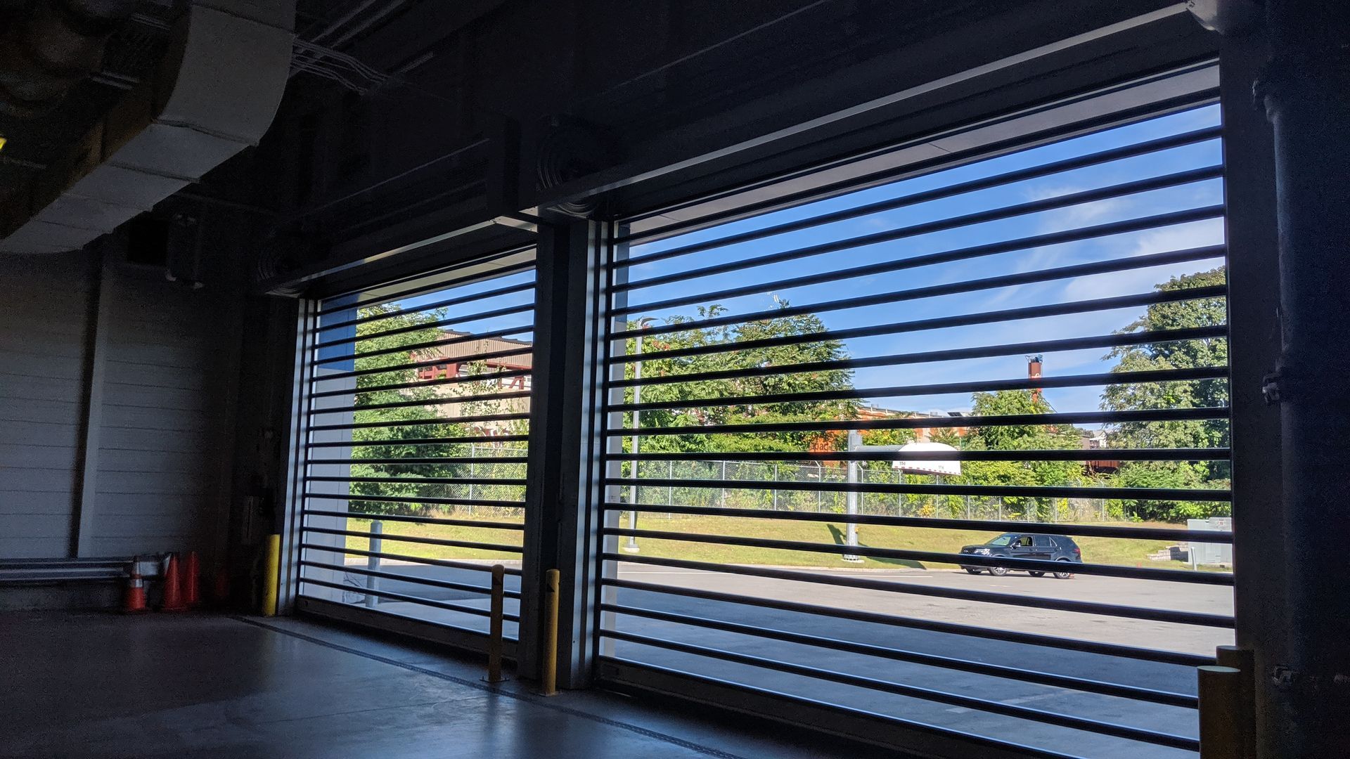 A car is parked in a parking garage with a sliding glass door.