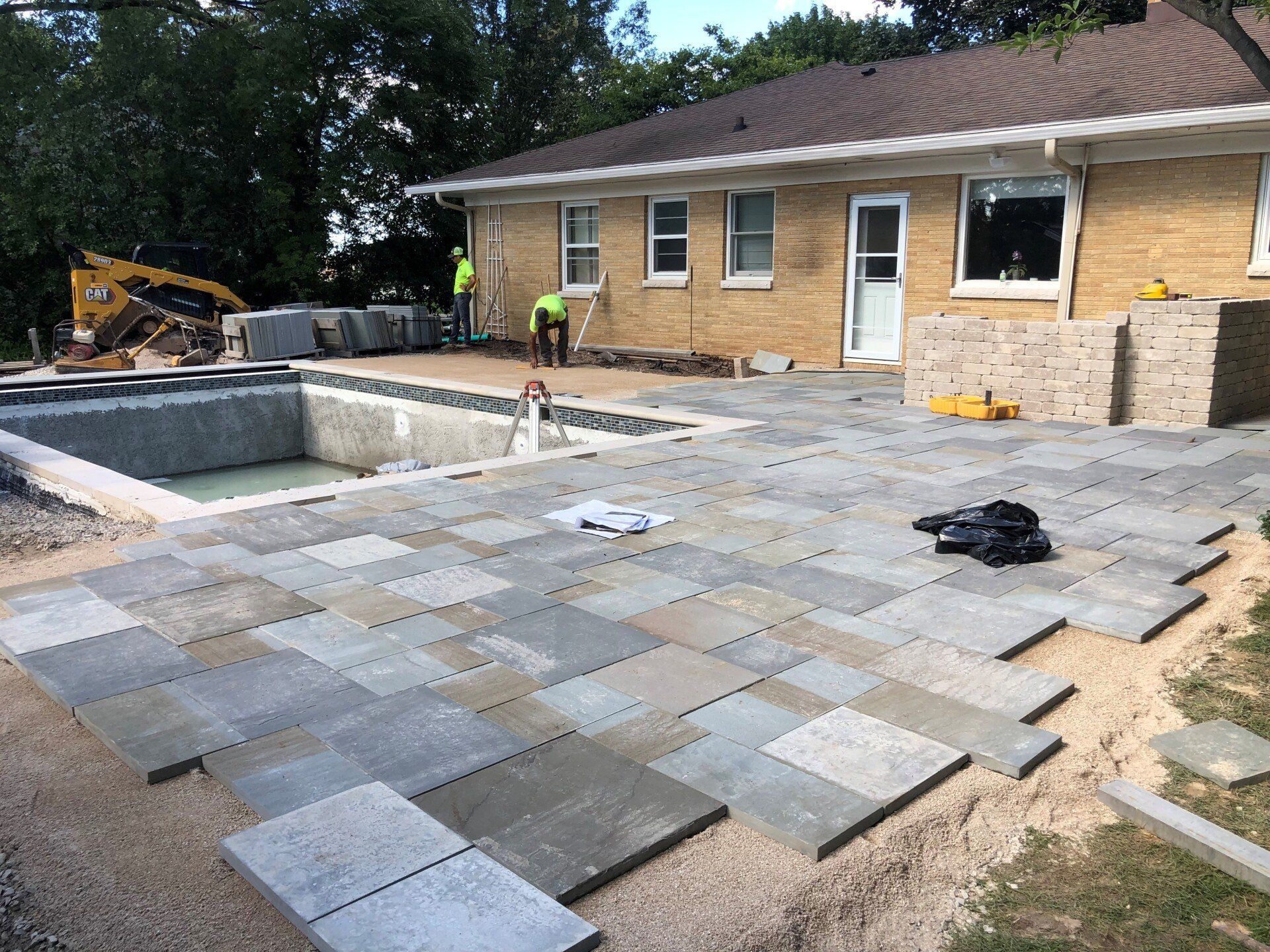 A brick house with a pool and a patio in front of it.