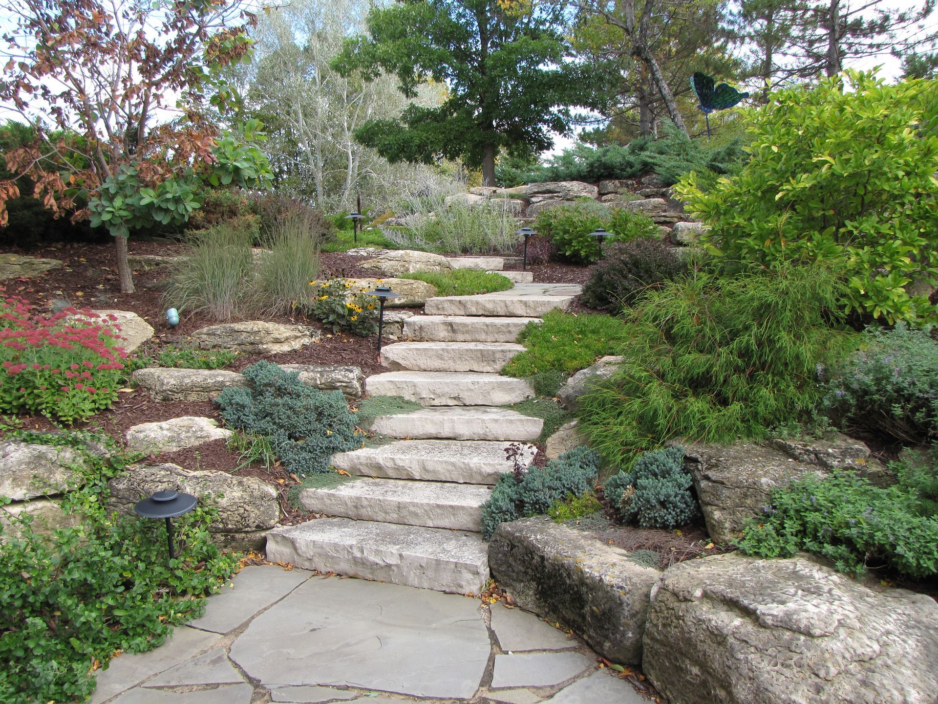 A stone walkway leading up to a set of stairs in a garden