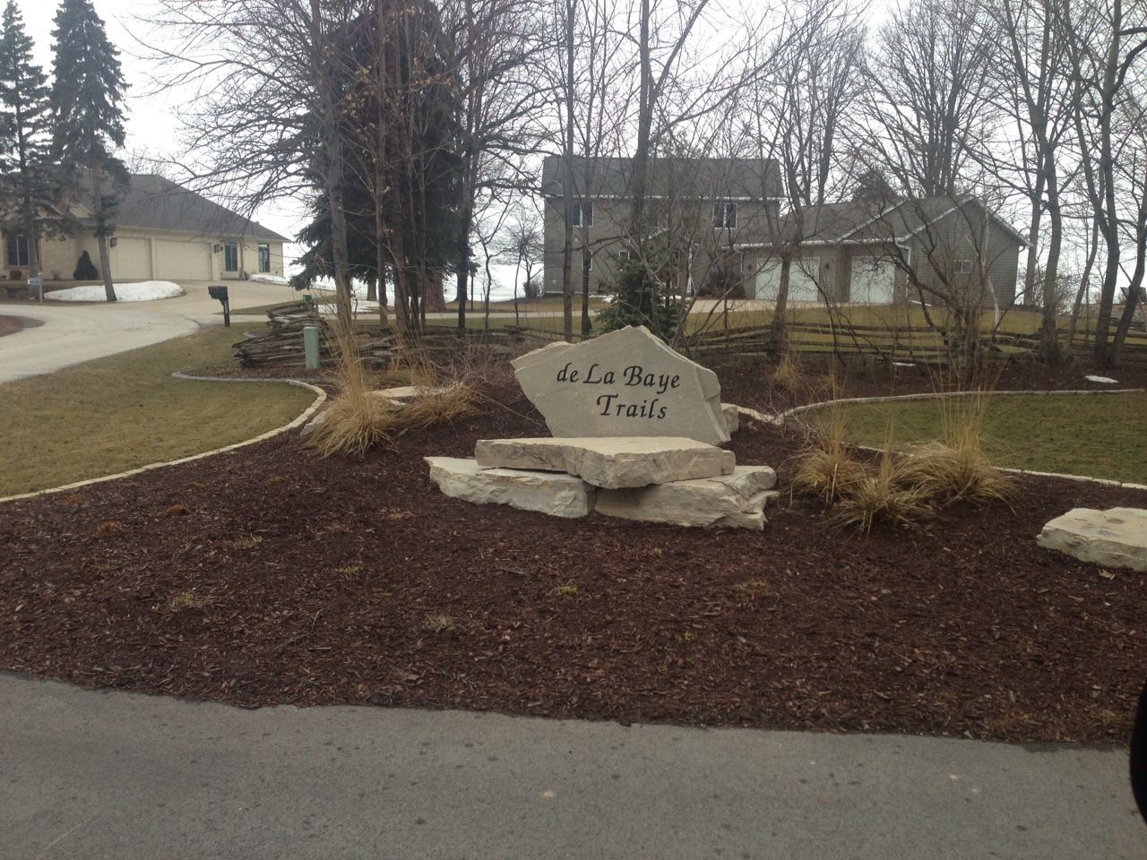A large rock  signage in the middle of a driveway