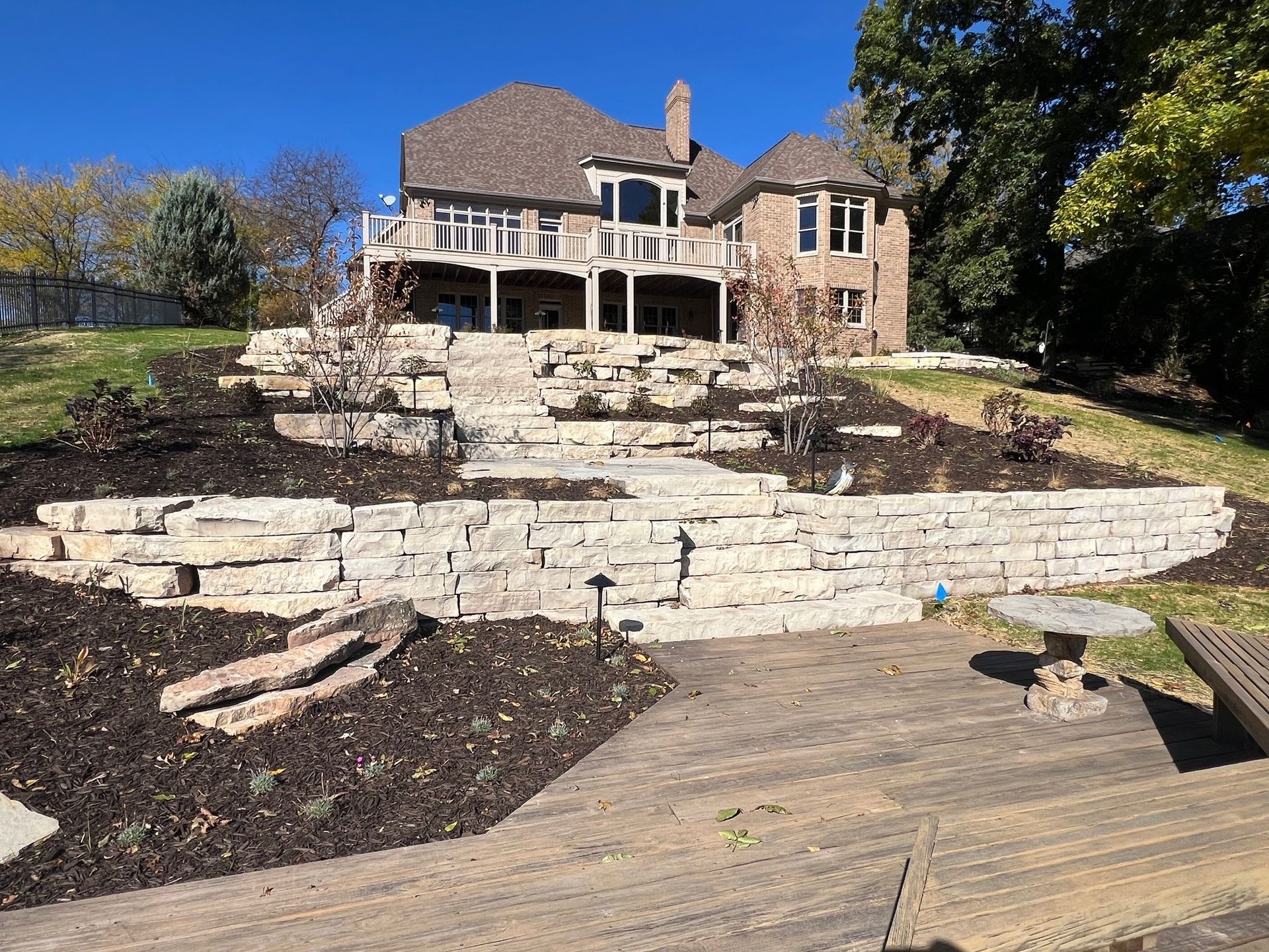 A large house is sitting on top of a hill next to a wooden deck