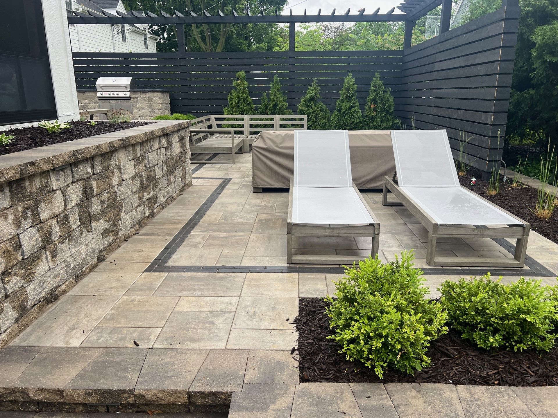 A patio with two lounge chairs and a grill